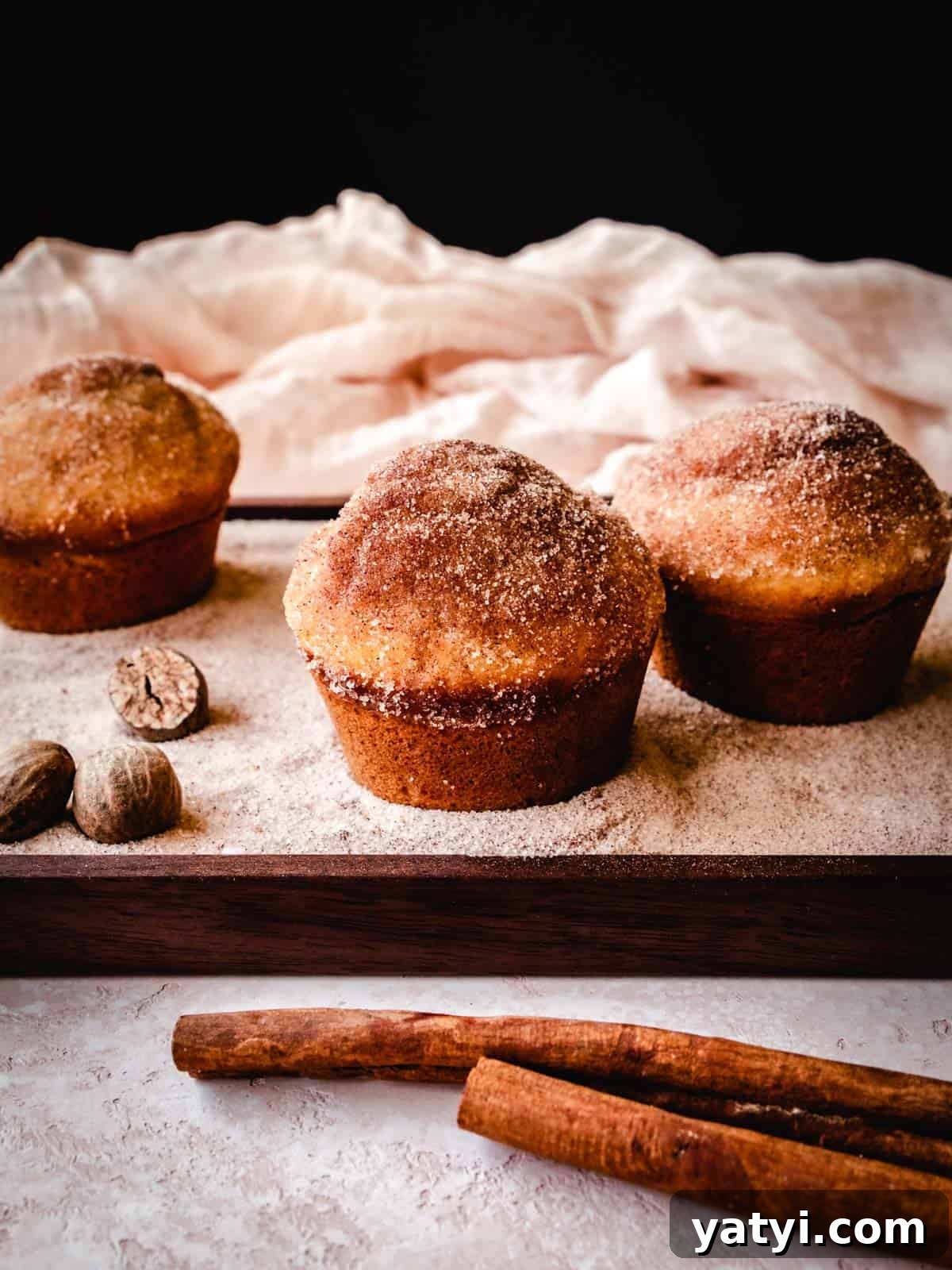 Cinnamon Sugar Donut Muffins Recipe — Soft Baked Donut-Style Muffins 9 cinnamon sugar donut muffins on a wood plate with whole nutmeg and cinnamon sticks