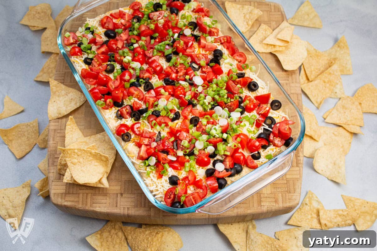Layered Taco Dip with Refried Beans for Parties and Game Day 2 Overhead view of layered taco dip with tortilla chips alongside.