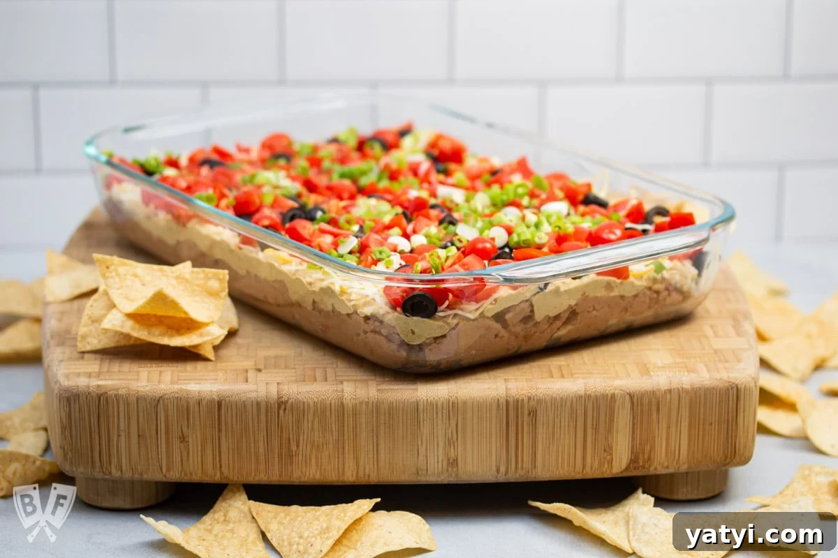 Layered Taco Dip with Refried Beans for Parties and Game Day 4 ΒΎ view of a layered taco dip with refried beans surrounded by tortilla chips.
