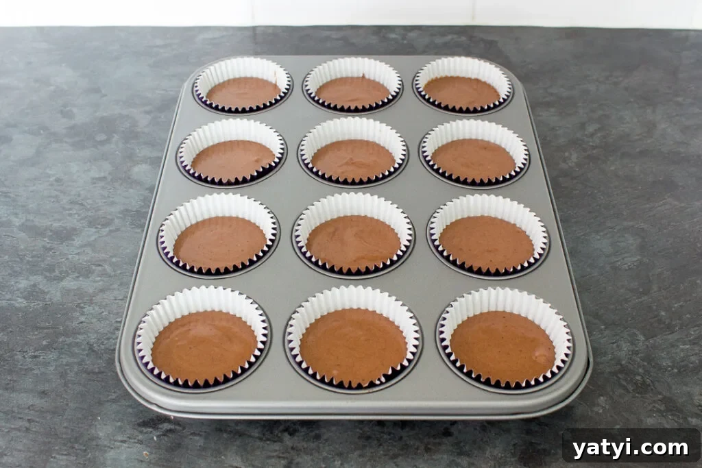 Bonfire Cupcakes Recipe: How to Make Campfire-Style Treats 7 Chocolate cupcake batter in cases set in a cupcake tin, ready to be baked in the oven.