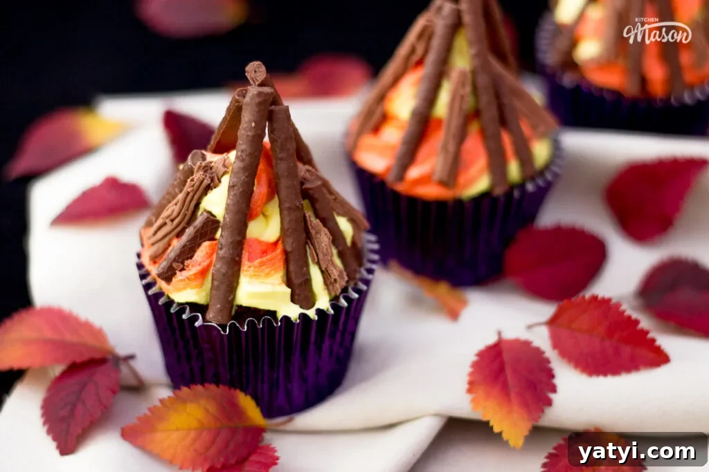 Bonfire Cupcakes Recipe: How to Make Campfire-Style Treats 13 Three bonfire cupcakes in purple cupcake cases, with red and orange leaves scattered around them.
