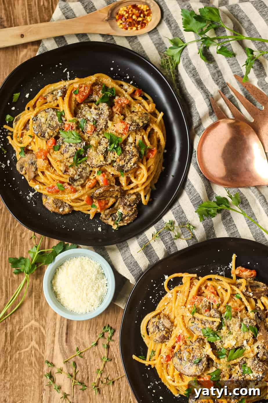 overhead shot of creamy cajun mushroom pasta on a black plate on wooden surface.