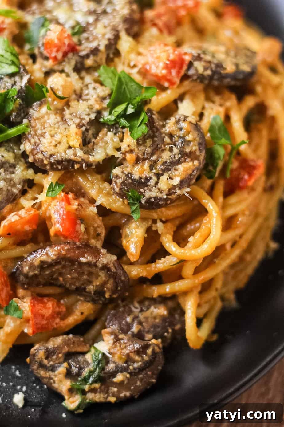 detail shot of creamy cajun mushroom pasta on a black plate on wooden surface.