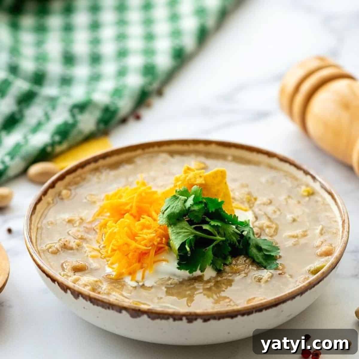 Cozy Chili Recipes Bowl of white chicken chili topped with sour cream and shredded cheddar.