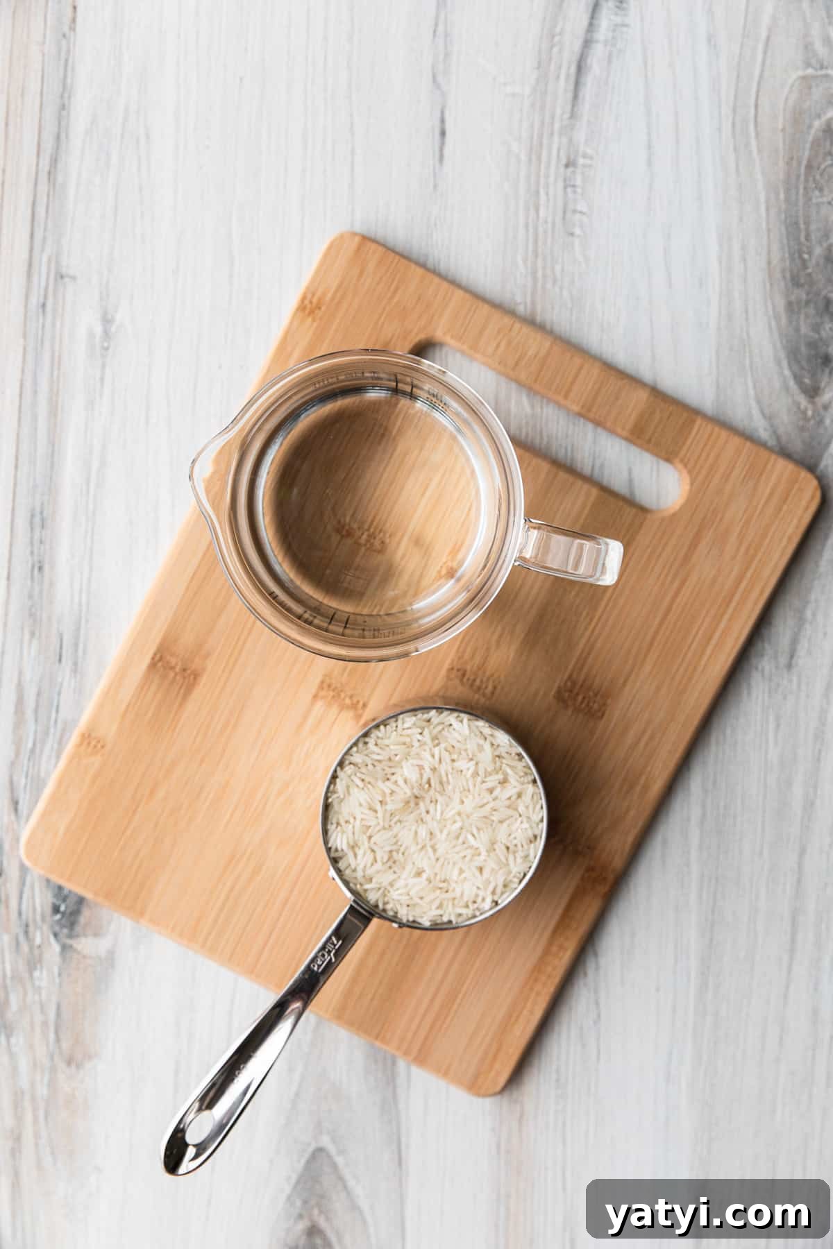 Perfect Instant Pot Basmati Rice Recipe in 15 Minutes 3 a cup of dry rice and a cup of water on a cutting board