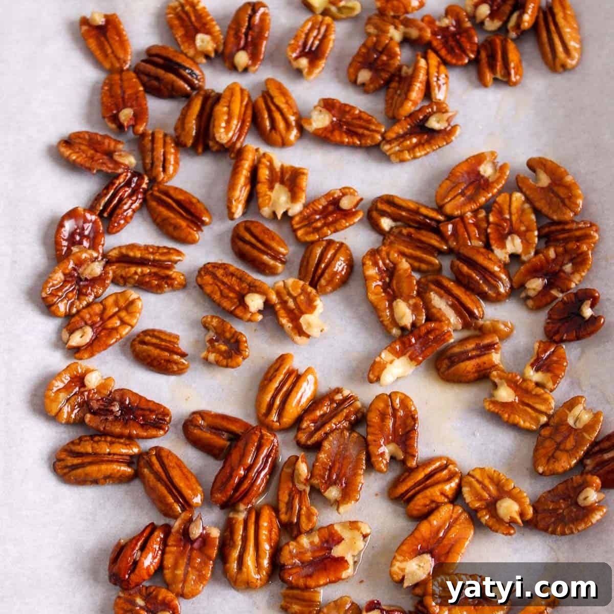 How to Make Chocolate-Covered Pecans at Home 5 Buttered pecans evenly spaced out on a baking sheet ready to be roasted.