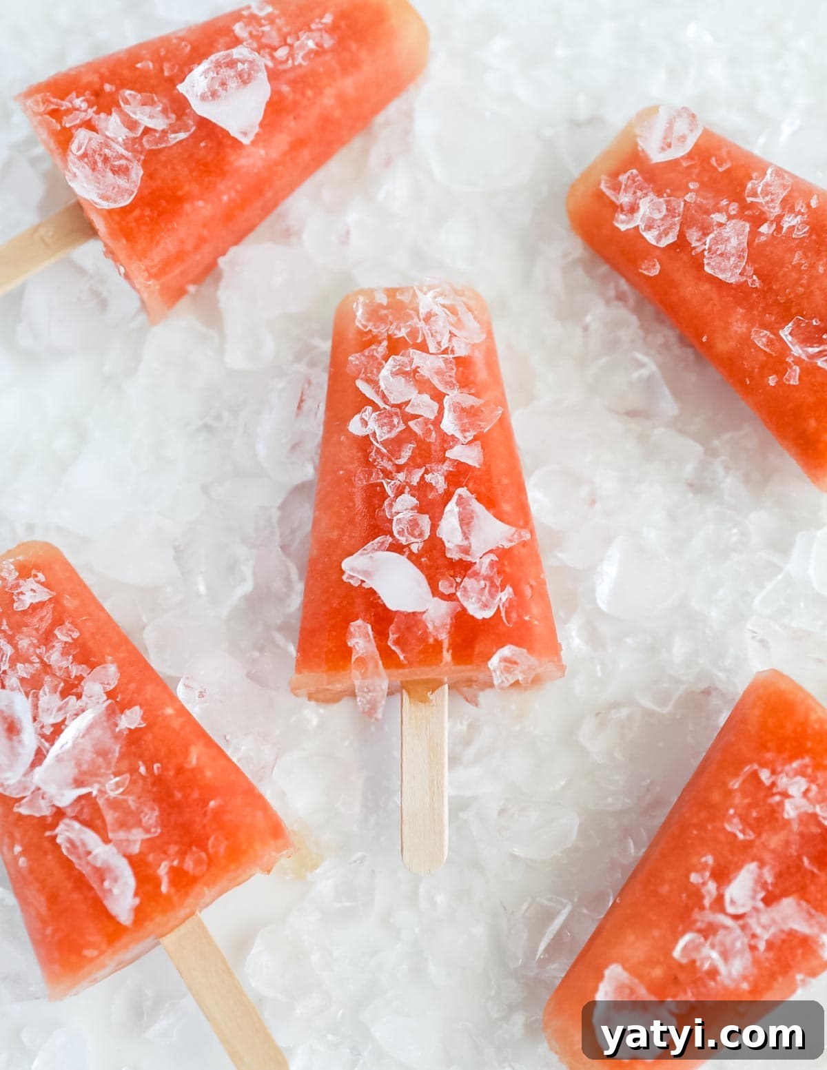 Refreshing Watermelon Pineapple Popsicle Recipe for Summer 2 Popsicles that are bright pink and covered in crushed ice