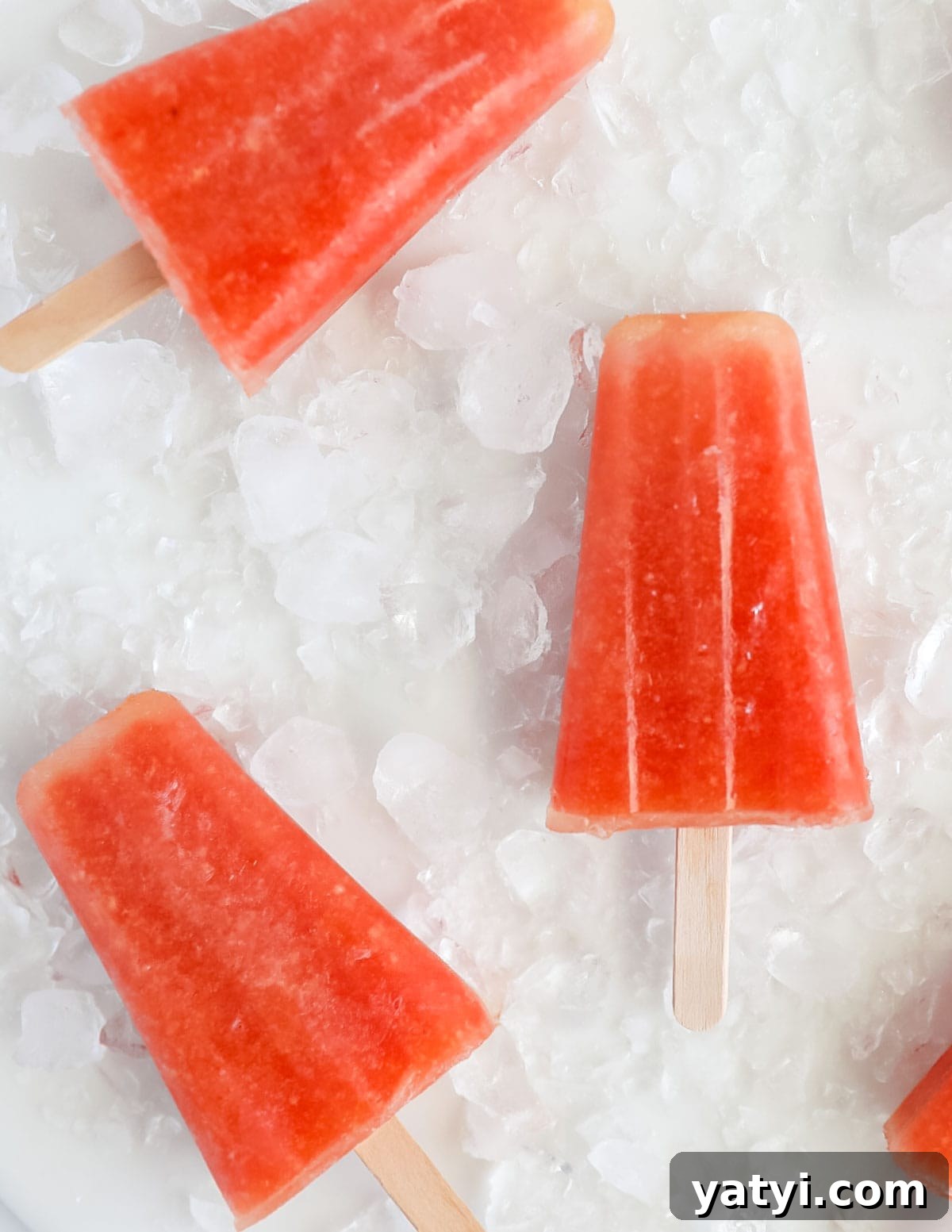 Refreshing Watermelon Pineapple Popsicle Recipe for Summer 4 Three pink popsicles on a bed of crushed ice