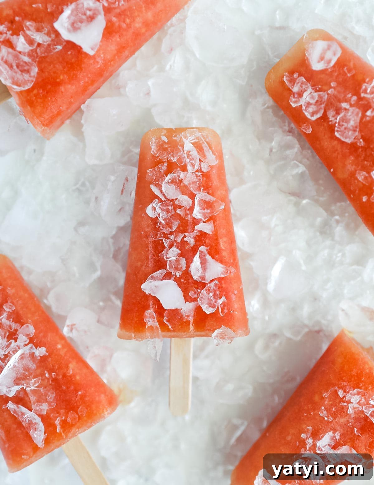 Refreshing Watermelon Pineapple Popsicle Recipe for Summer 5 an overhead picture of pink popsicles that have crushed ice on and around them
