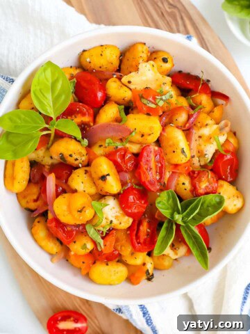 A bowl filled with gnocchi, vegetables, and basil.