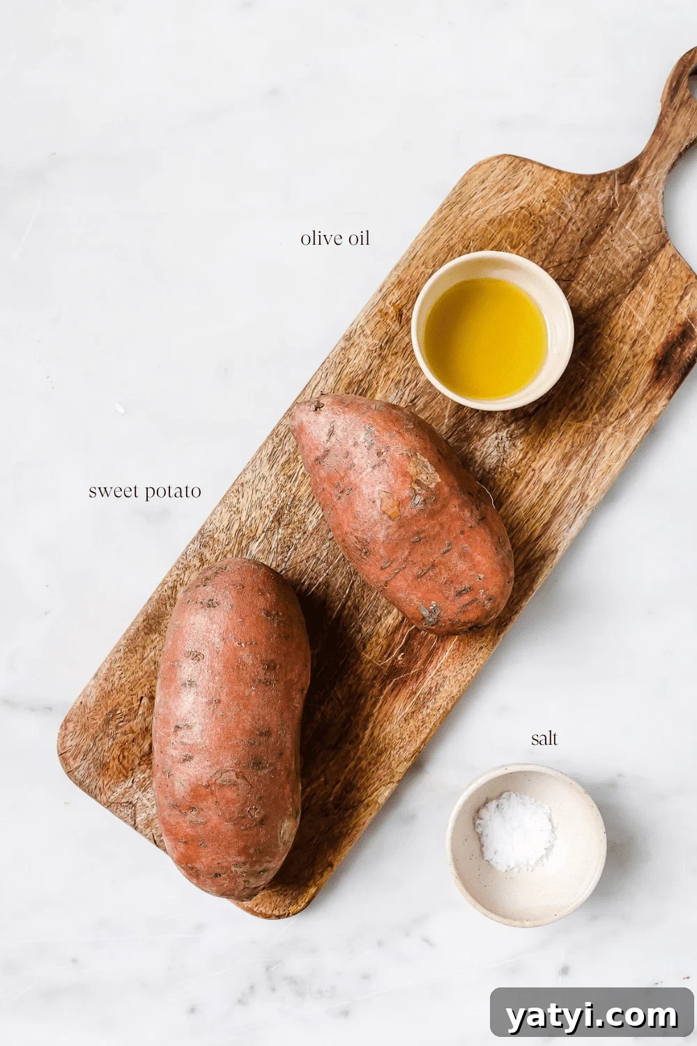 Crispy Air Fryer Sweet Potatoes: Quick Roast in 20 Minutes 3 Ingredients prepped and set out on a wooden cutting board.