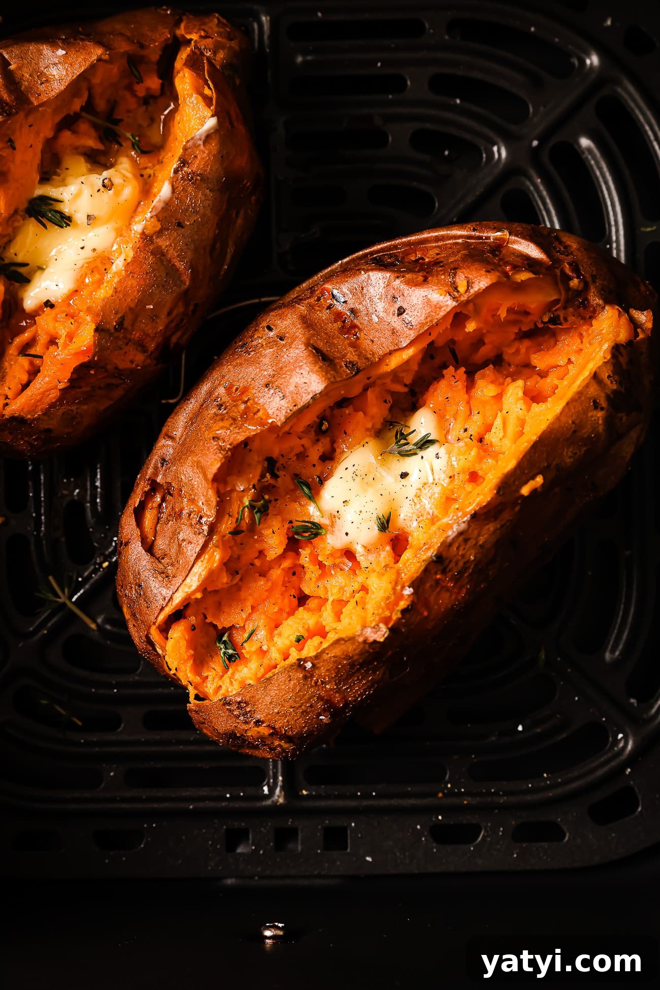 Crispy Air Fryer Sweet Potatoes: Quick Roast in 20 Minutes 9 An overhead view of a sweet potato with butter and herbs in the air fryer.