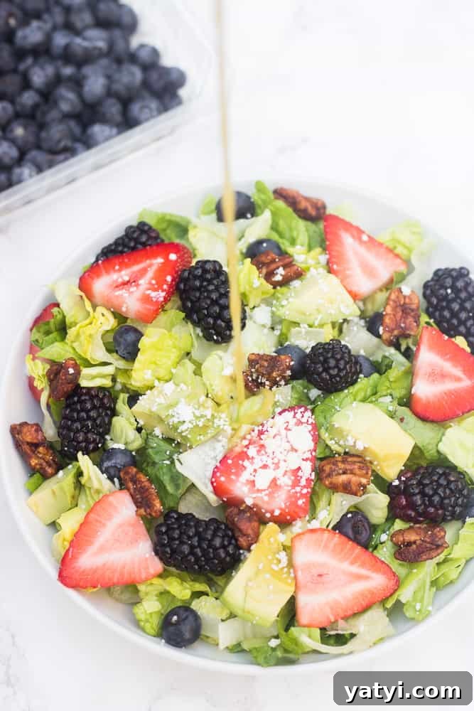 This red, white, blue summer berry salad is loaded with fresh fruit, topped with avocado slices, feta cheese, & candied nuts, and drizzled with a naturally-sweetened lemon poppyseed dressing