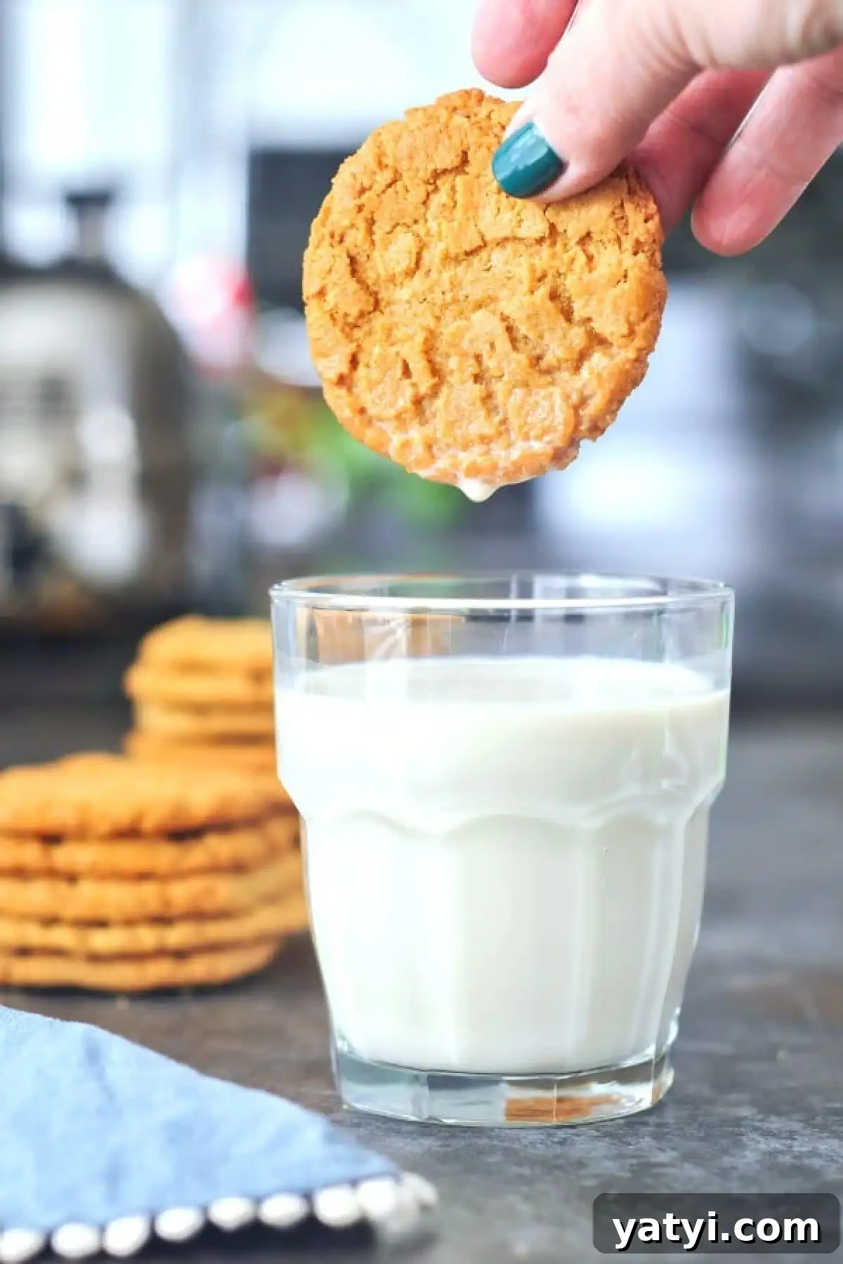 Flourless Almond Flour Cookies @spabettie A hand dunking a flourless almond butter cookie into a glass of milk.