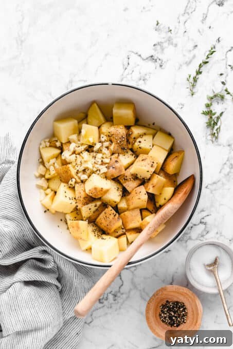 Season. ingredients for roasted potatoes in a bowl with thyme, black pepper and salt beside it