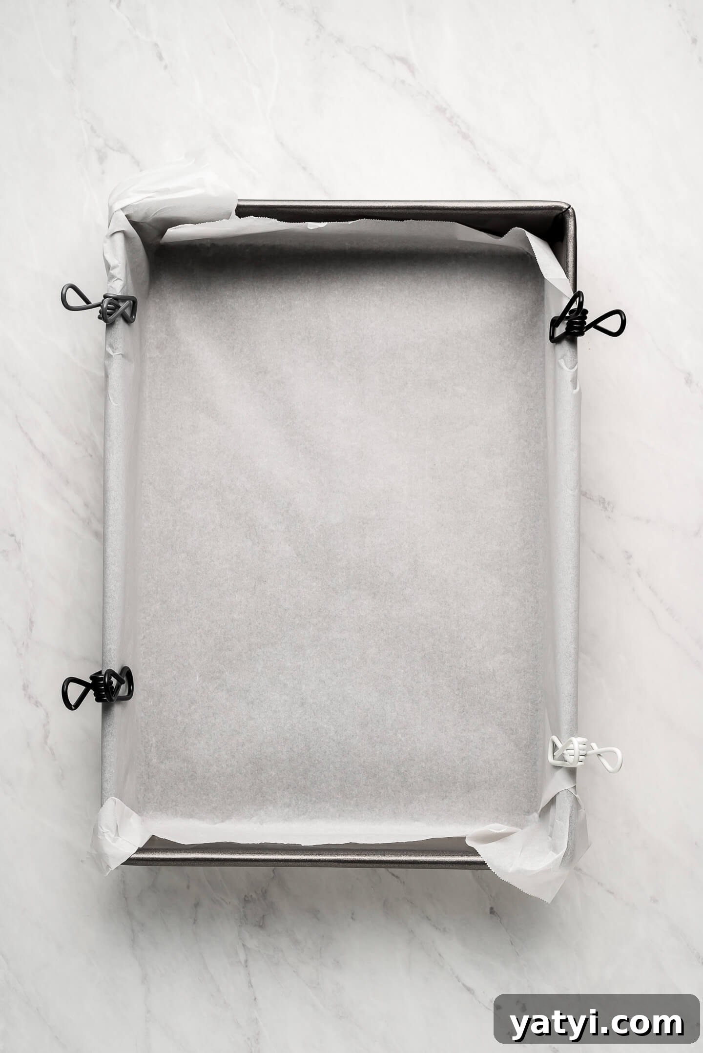 Ultimate Rice Krispie Treats Recipe You’ll Love 2 9x13 inch pan lined with parchment paper with chip clips holding it on the sides.