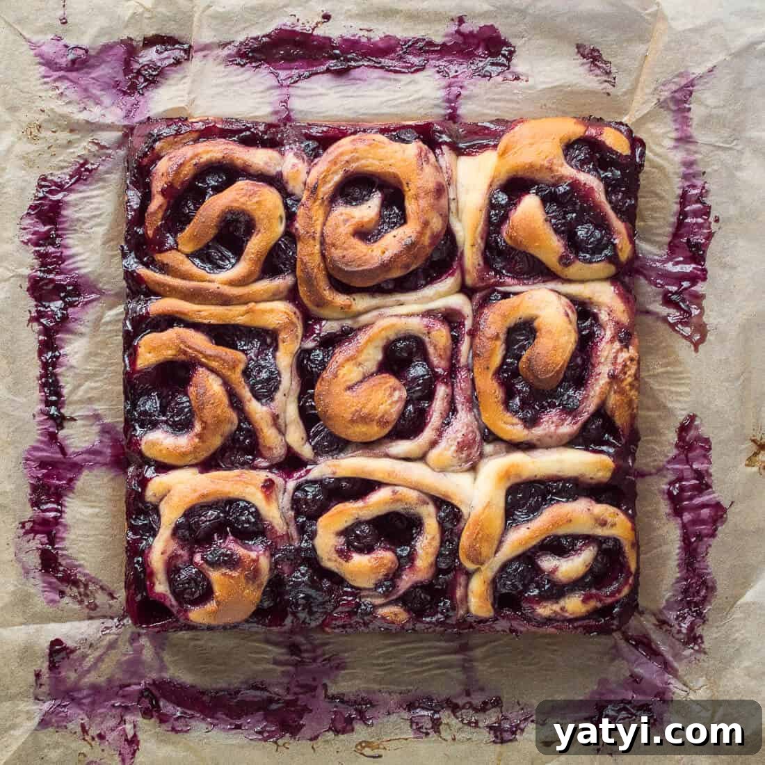 Citrus Lemon Blueberry Rolls (Vegan) 4 Nine vegan lemon blueberry rolls in a square on a sheet of baking parchment.