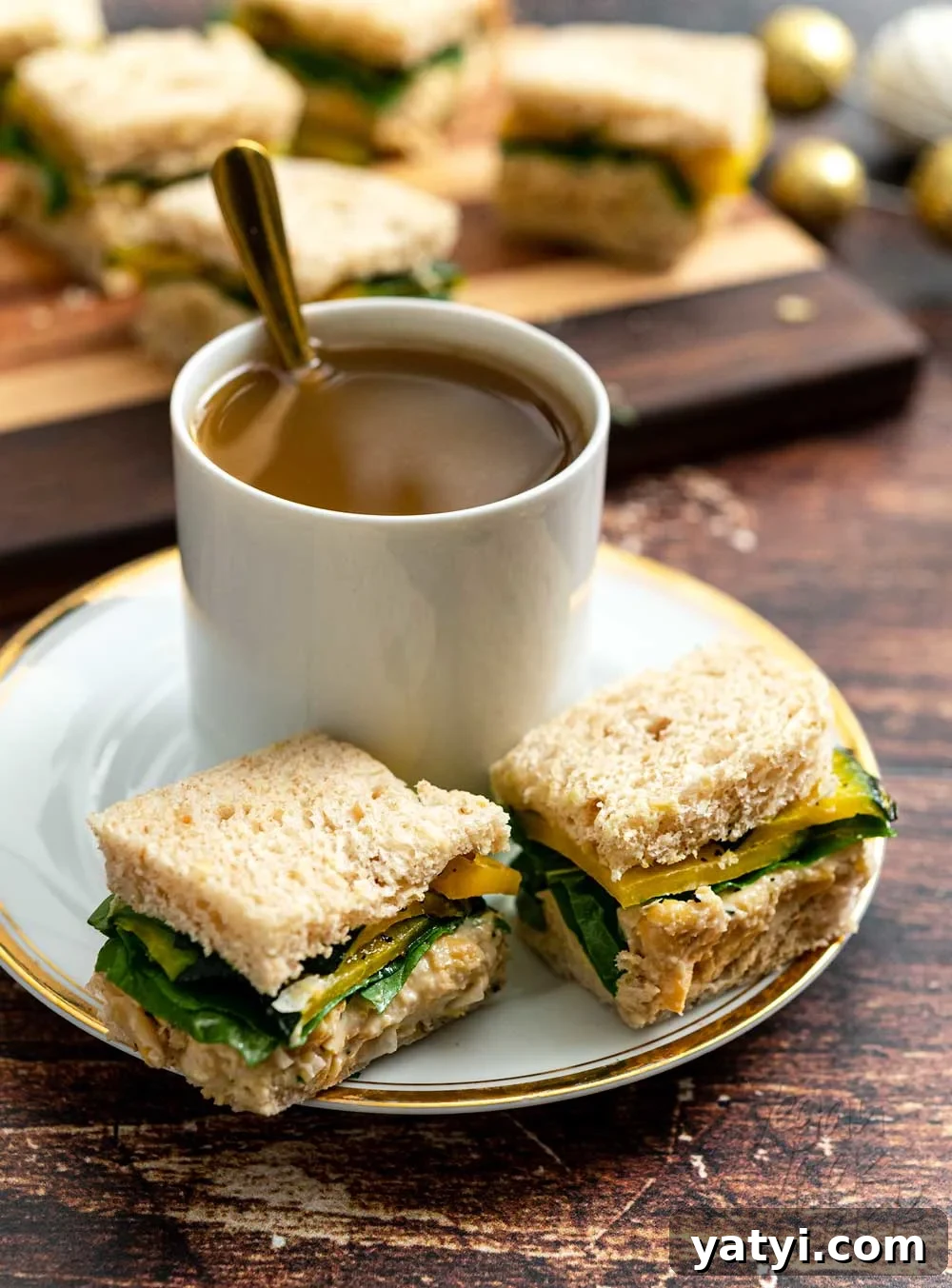 Vegan Holiday Afternoon Tea Menu & Festive Recipes 9 Small tea sandwiches on a saucer with a mug of milky tea