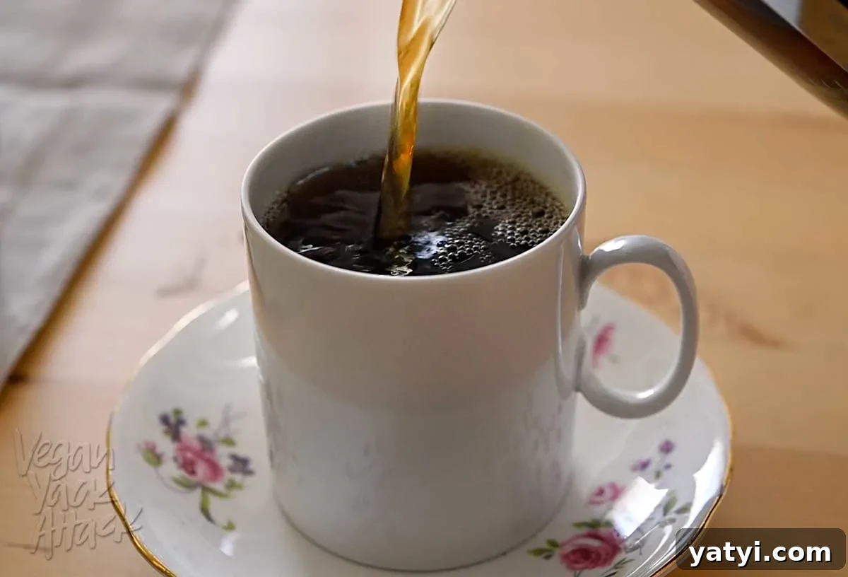 Vegan Holiday Afternoon Tea Menu & Festive Recipes 3 Tea being poured into a white tea cup sitting on a floral saucer