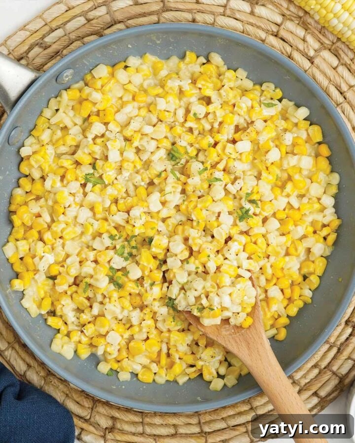 Skillet of honey butter corn with wooden spoon.