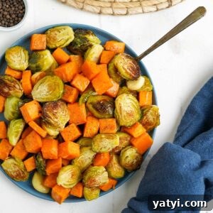 Bowl of brussel sprouts and sweet potatoes with a fork.