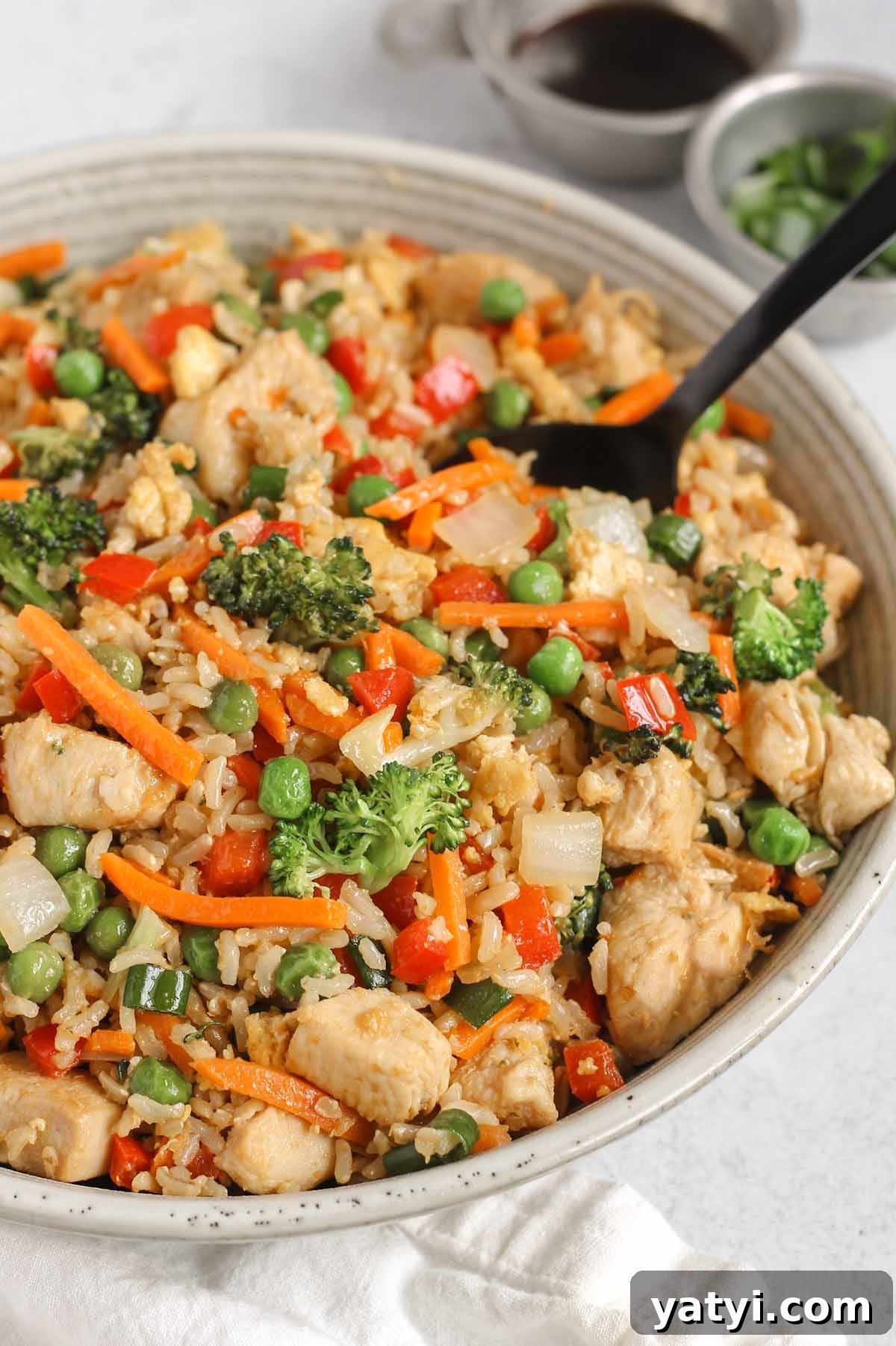 Low-Sodium Fried Rice Without Soy Sauce — Flavorful Vegetable Fried Rice 8 Chicken fried brown rice in a serving bowl with a black spoon.