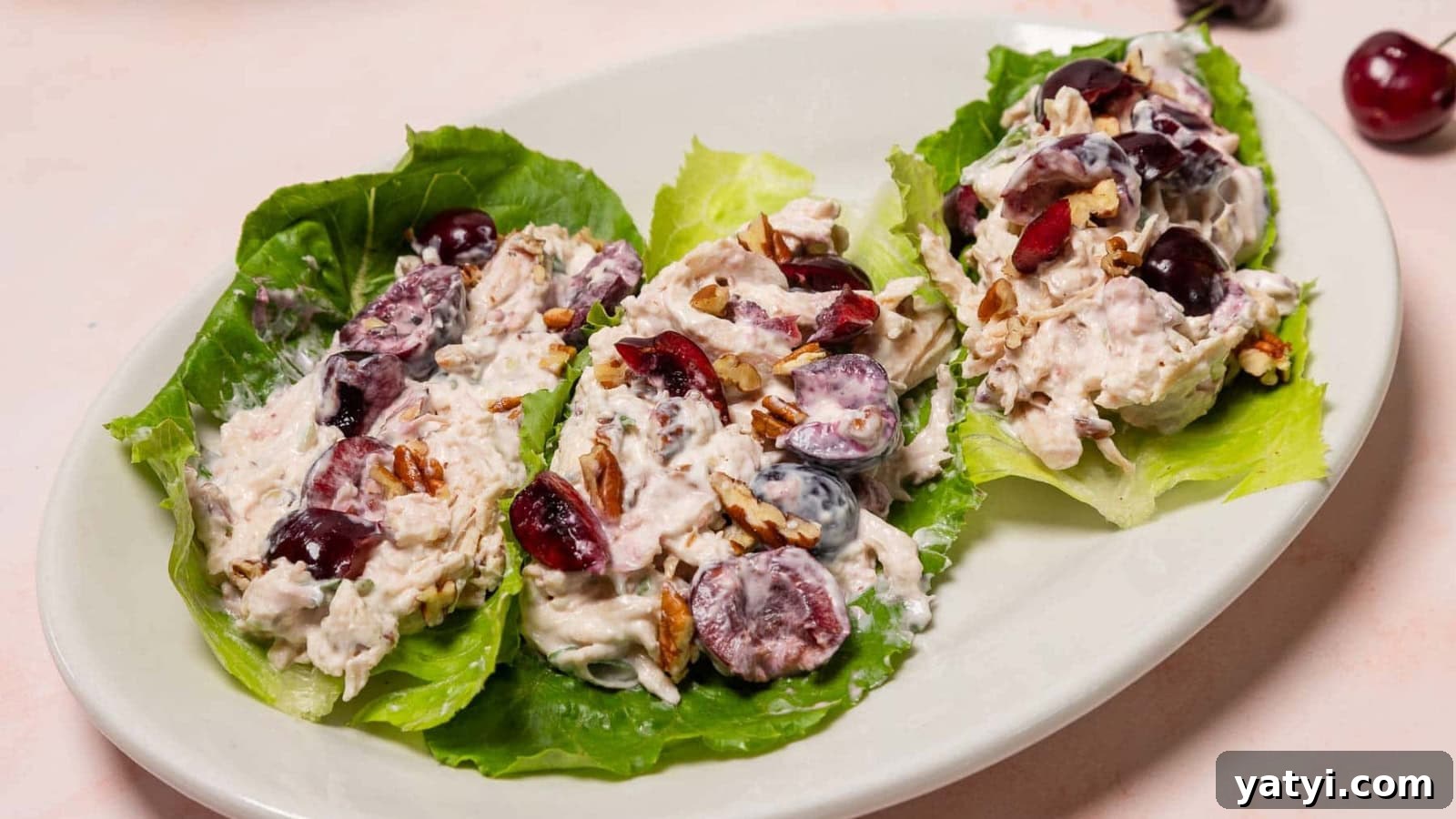 19 Holiday Side Dishes to Balance Your Festive Meal 20 Three lettuce leaves topped with chicken salad, grapes, and pecans on a white oval plate.