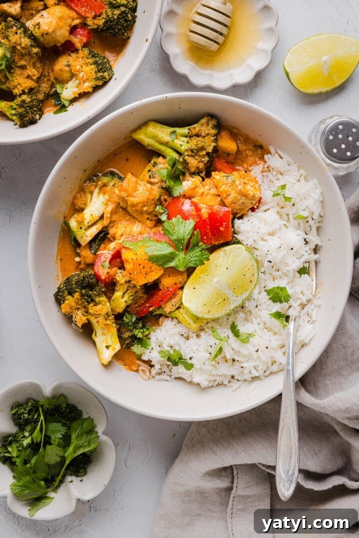 Slow Cooker Thai Red Curry with Chicken and Coconut Milk 8 Thai-inspired red curry with chicken and vegetables in a serving bowl with rice and lime.