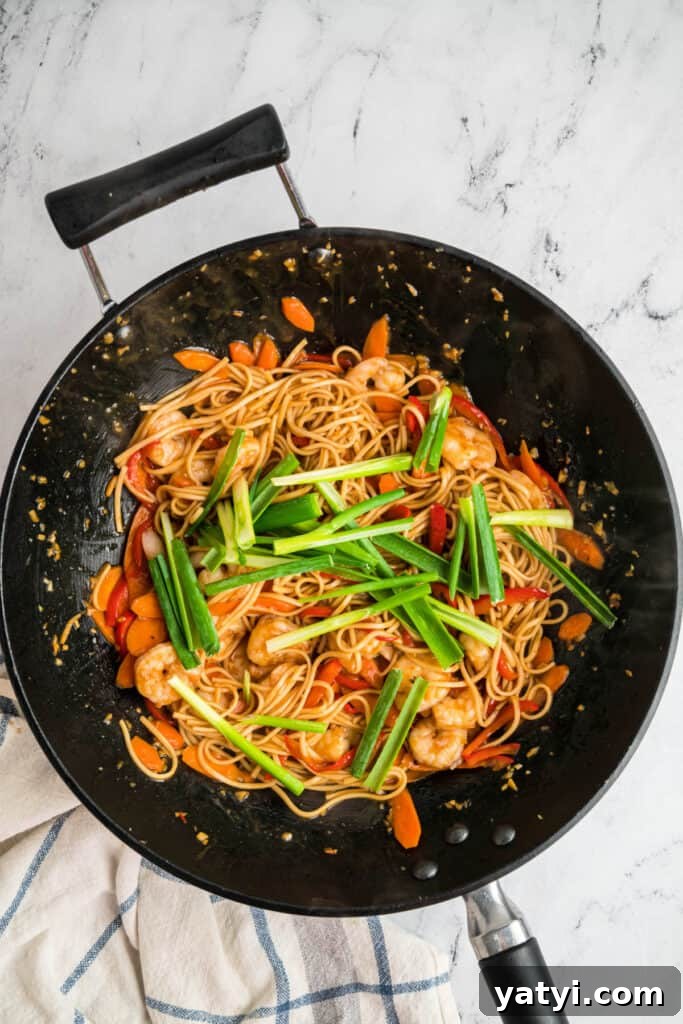 Garlic Shrimp Lo Mein Recipe — Quick Stir-Fry Noodles 14 Green onions added on top of the shrimp lo mein in a wok before final mixing.