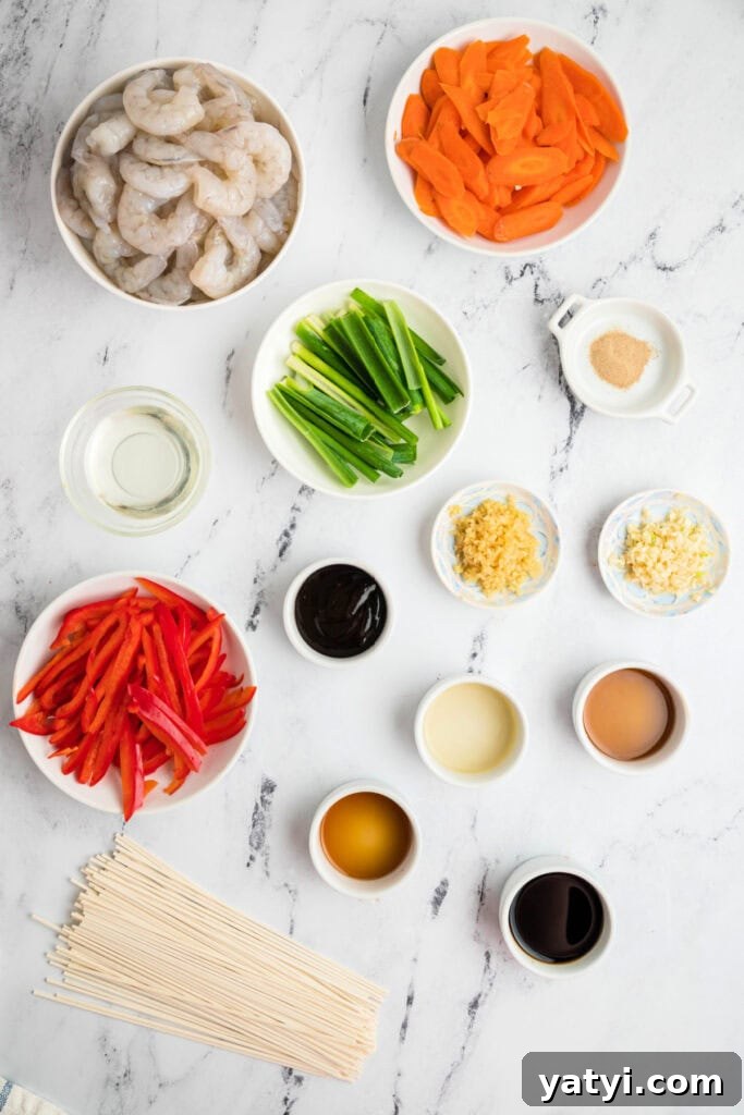 Garlic Shrimp Lo Mein Recipe — Quick Stir-Fry Noodles 3 Overhead view of raw shrimp, sliced carrots, red bell pepper, green onions, garlic, ginger, and lo mein sauce ingredients laid out on a marble surface.
