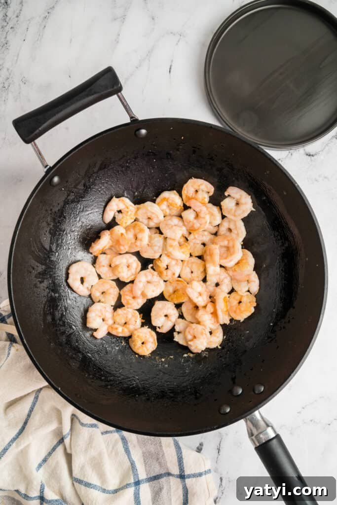 Garlic Shrimp Lo Mein Recipe — Quick Stir-Fry Noodles 7 Shrimp cooking in a wok until pink and lightly browned.