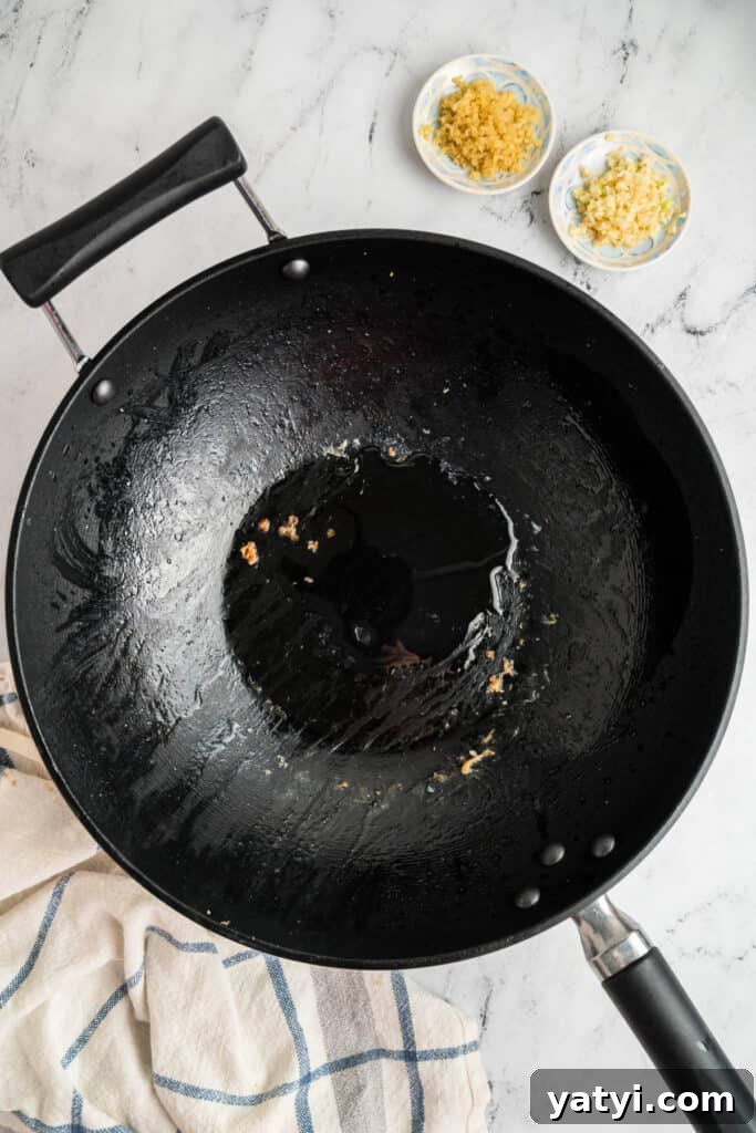 Garlic Shrimp Lo Mein Recipe — Quick Stir-Fry Noodles 8 Empty wok with oil and bits of garlic and ginger left after cooking shrimp.
