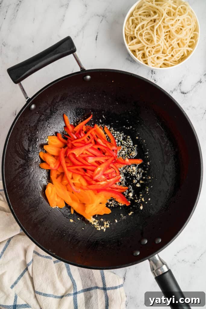 Garlic Shrimp Lo Mein Recipe — Quick Stir-Fry Noodles 9 Carrots and red bell pepper strips added to the wok with garlic and ginger.