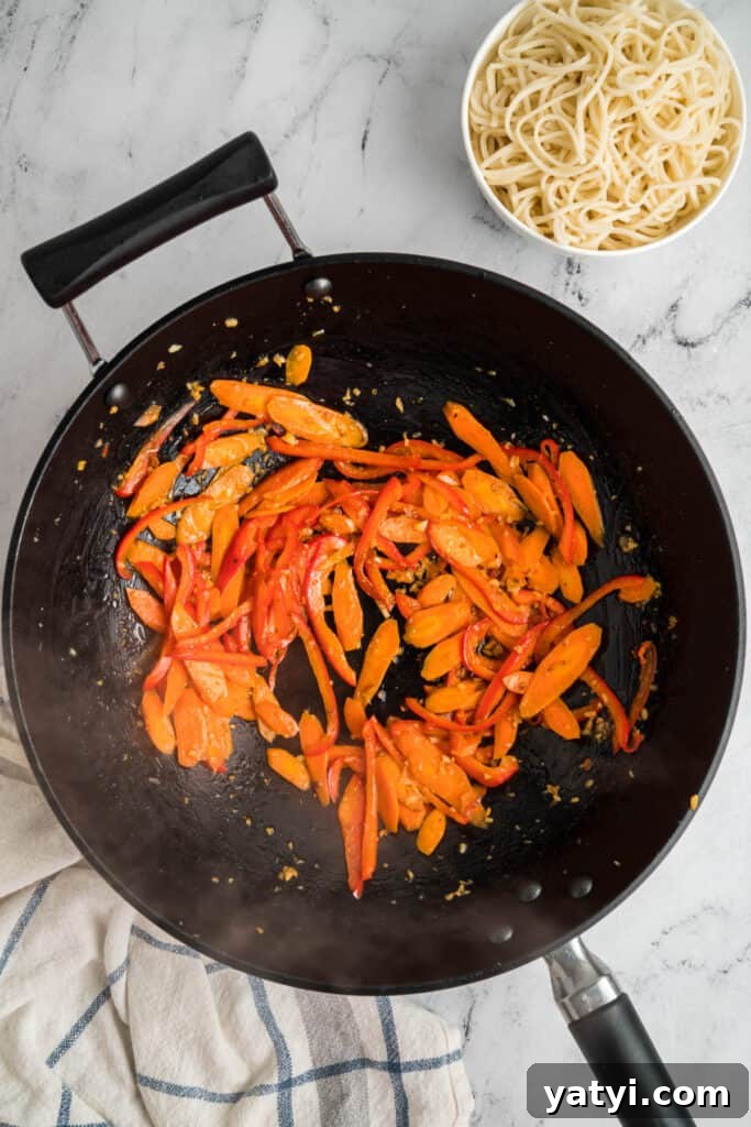 Garlic Shrimp Lo Mein Recipe — Quick Stir-Fry Noodles 10 Sautéed carrots and red bell peppers cooking in the wok with garlic and ginger.