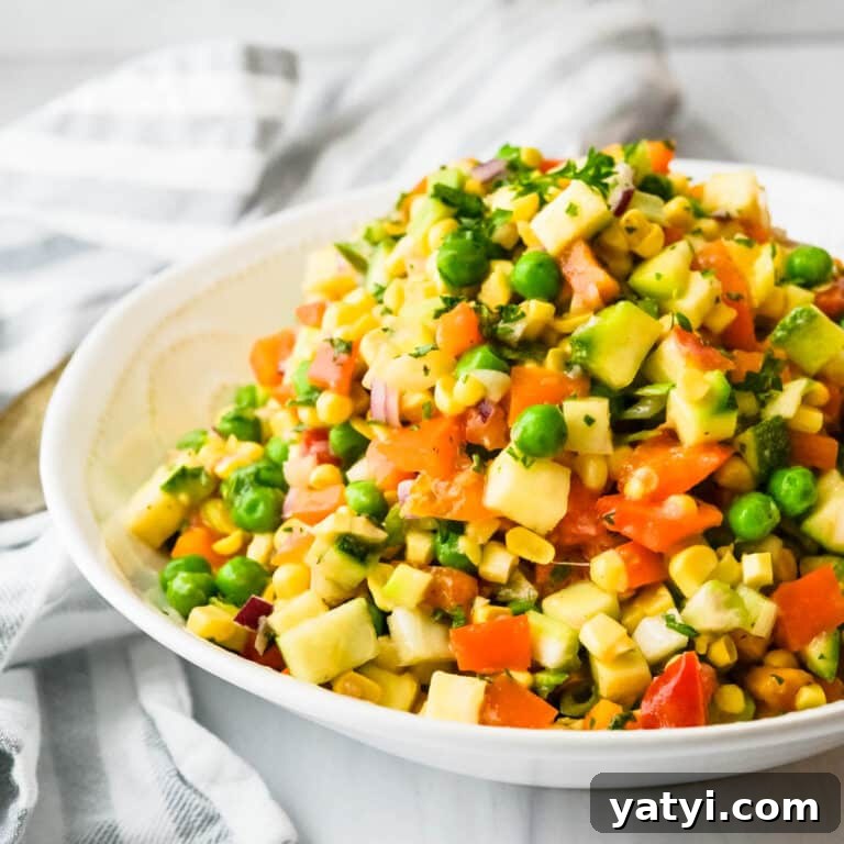 Summer Chopped Vegetable Salad with Creamy Shallot Vinaigrette 9 Serving a chopped vegetable salad in a white bowl.