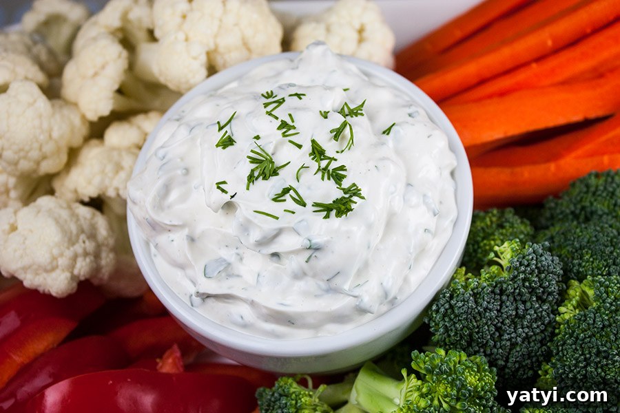 Fresh Herb Veggie Dip Recipe for Parties and Snacks 3 Fresh Herb Vegetable Dip in a white bowl surrounded by cut broccoli, cauliflower, carrots, and red bell peppers.