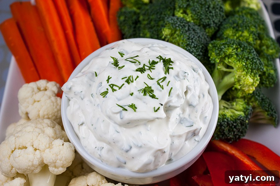 Fresh Herb Veggie Dip Recipe for Parties and Snacks 5 Fresh Herb Vegetable Dip in a white bowl surrounded by cut broccoli, cauliflower, carrots, and red bell pepper