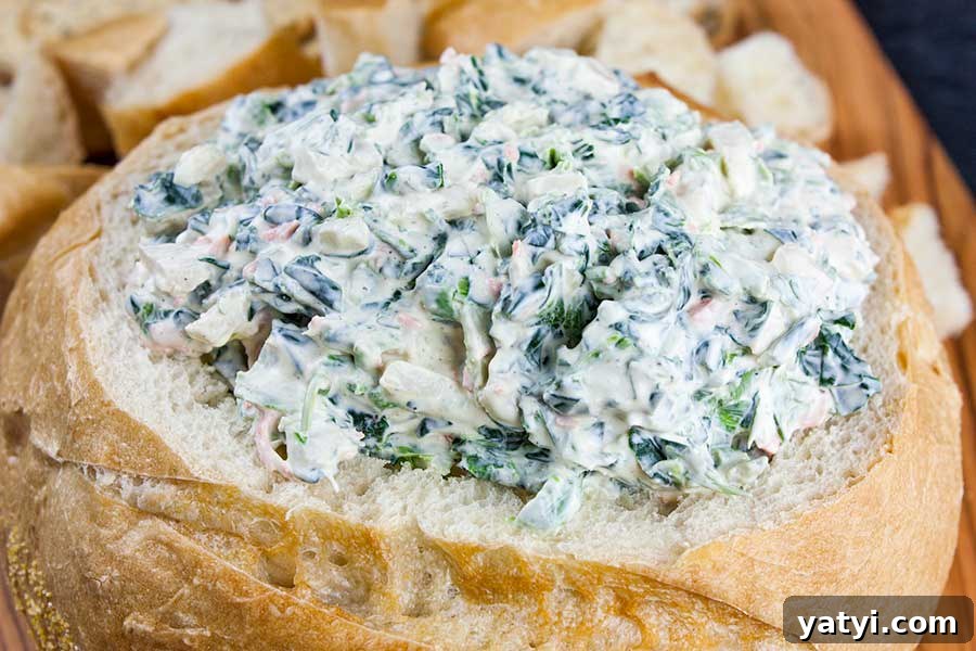 Fresh Herb Veggie Dip Recipe for Parties and Snacks 7 Easy spinach dip in a bread bowl surrounded by bread cubes.