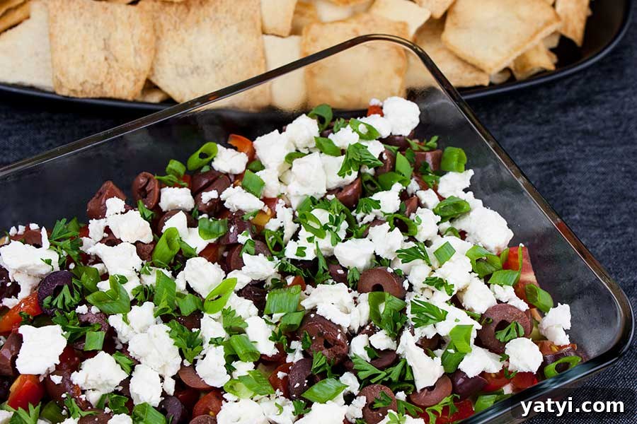 Fresh Herb Veggie Dip Recipe for Parties and Snacks 8 Easy Mediterranean dip in a glass baking dish with pita chips in the background.