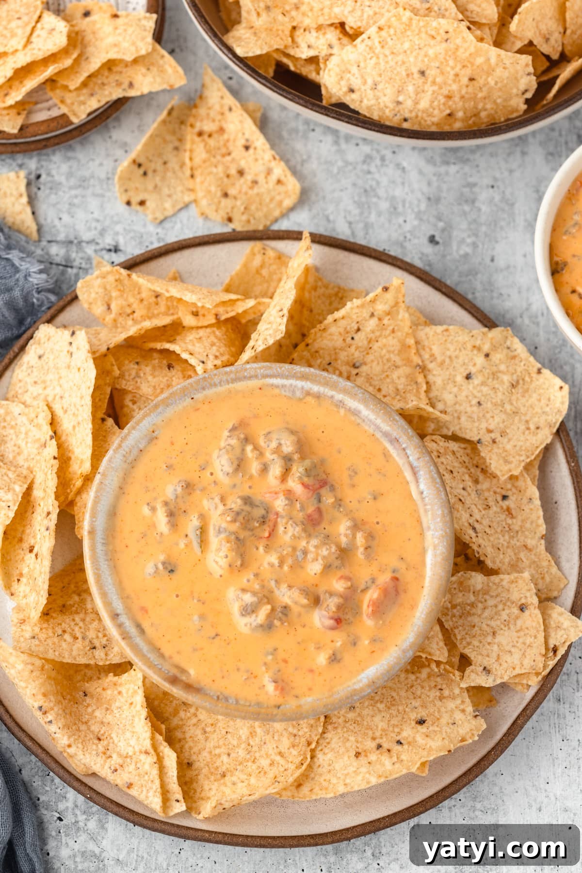 Creamy Velveeta Sausage Dip Recipe for Parties and Game Day 9 A bowl of creamy cheese dip with sausage and diced tomatoes, accompanied by a plate of tortilla chips.