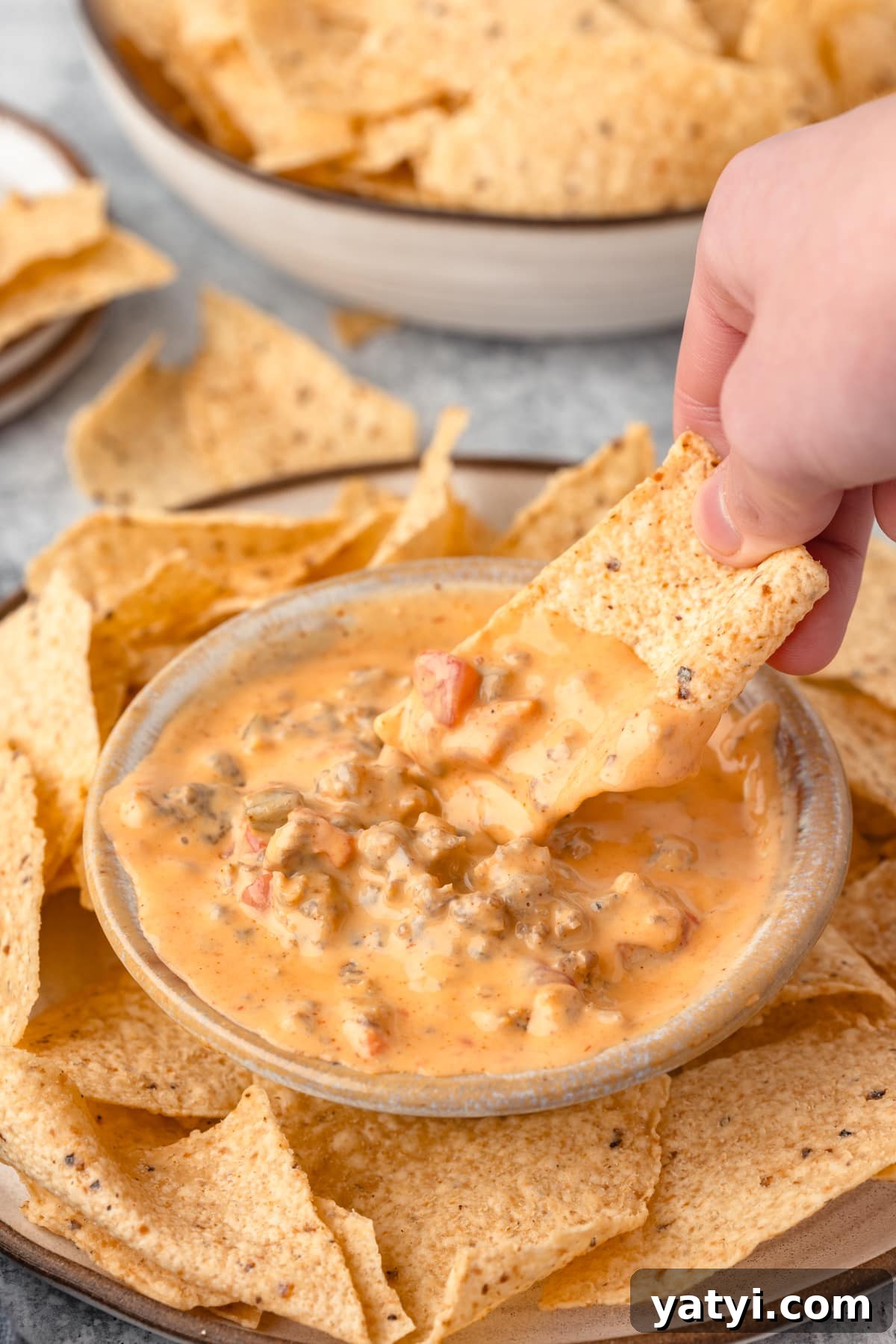Creamy Velveeta Sausage Dip Recipe for Parties and Game Day 10 a hand dipping a tortila chip into creamy velveeta sausage dip