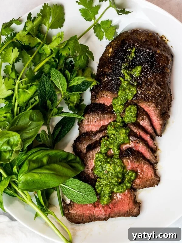 Asian marinated flank steak, spicy Asian chimichurri steak with fresh herbs on a white plate
