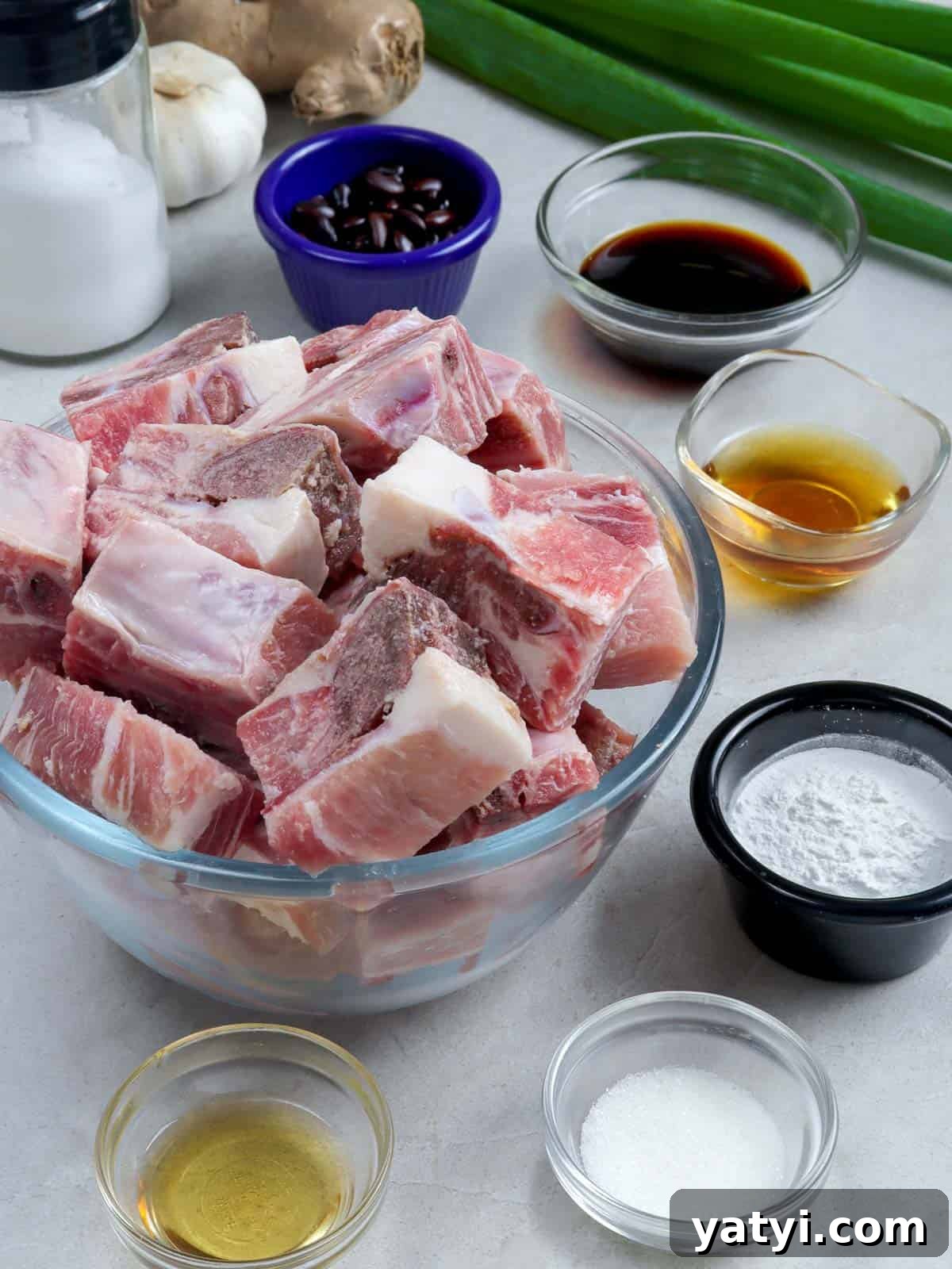 Steamed Spareribs with Fermented Black Beans Recipe 3 cut spare ribs in a bowl with black beans, soy sauce, and green onions on the side