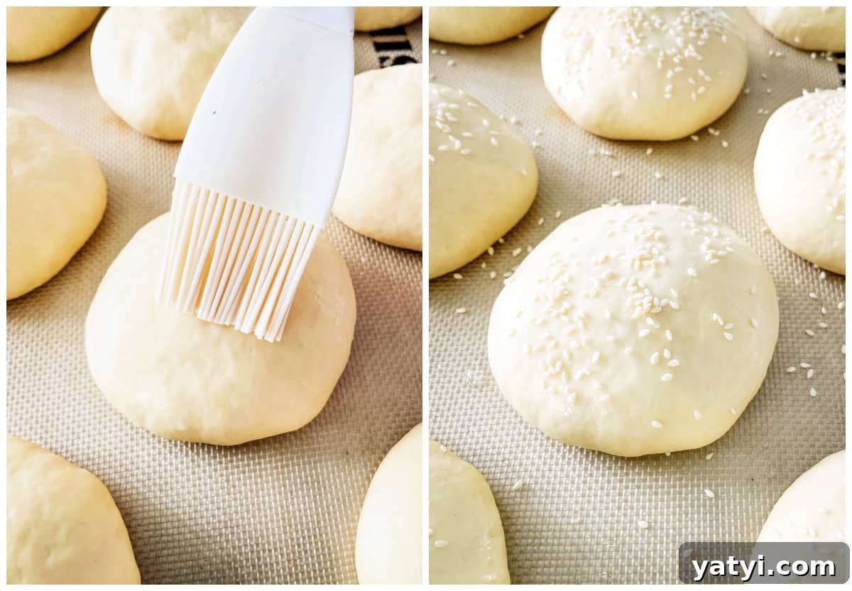 Soft Homemade Hamburger Buns: Fluffy Recipe for Tender Buns 4 hamburger bun dough being brushed with sesame seeds