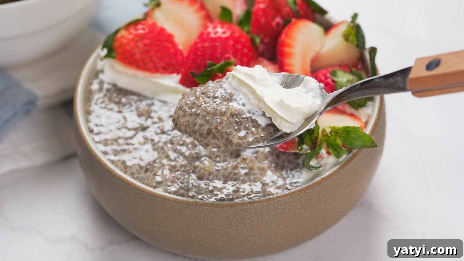 21 Snack Swaps That Beat Junk Food Without Sacrificing Flavor 19 A bowl of chia pudding topped with sliced strawberries and a dollop of whipped cream, with a spoon lifting a portion.