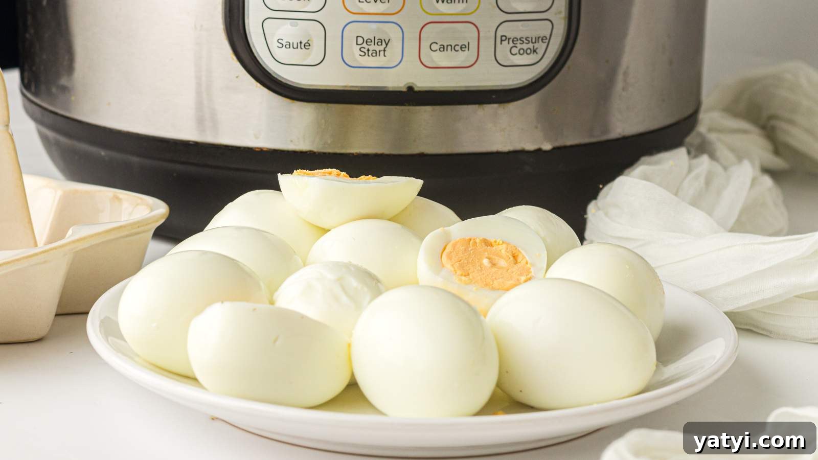 21 Snack Swaps That Beat Junk Food Without Sacrificing Flavor 20 A plate of peeled hard-boiled eggs is placed in front of an instant pot on a white countertop.