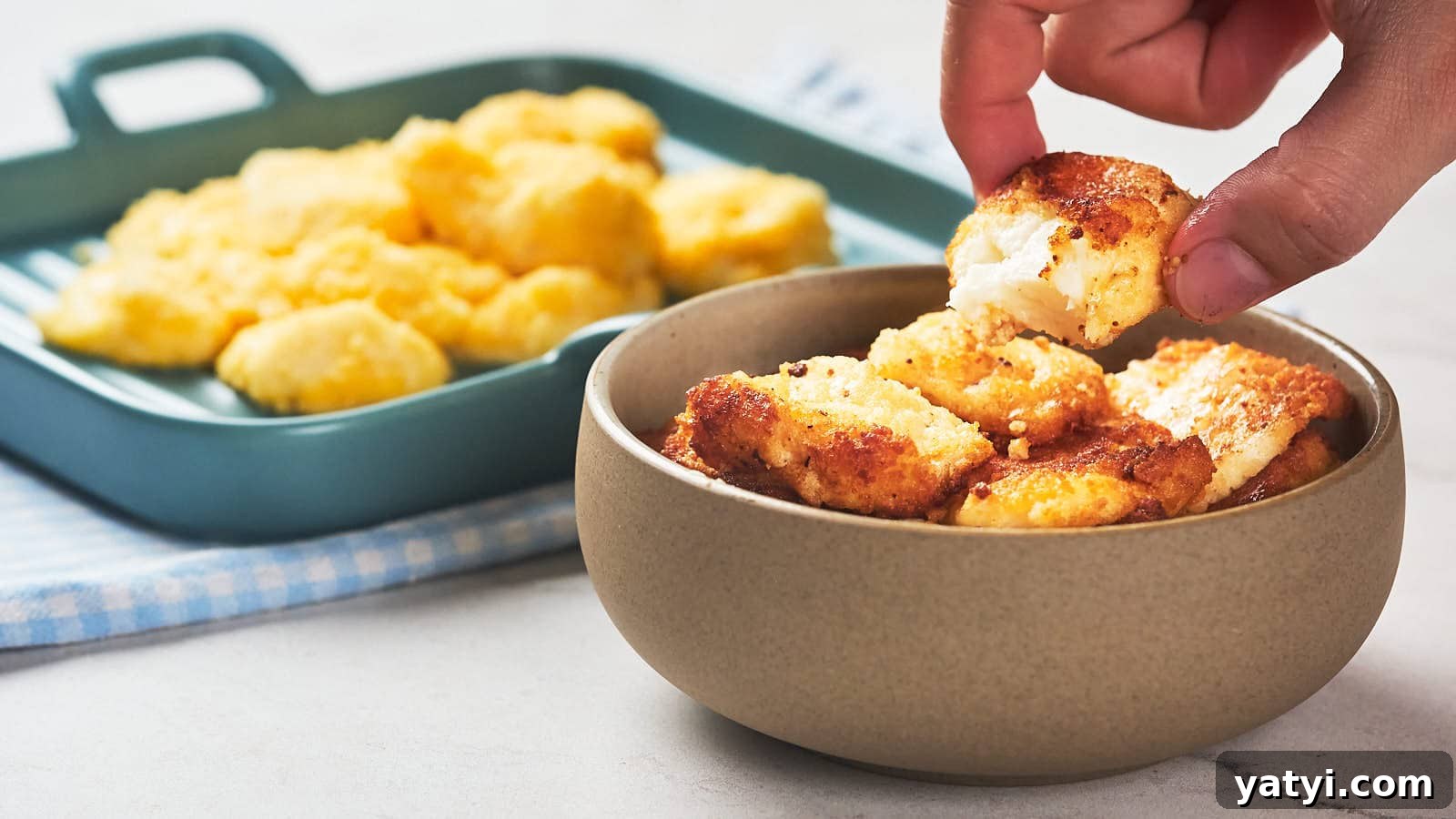 21 Snack Swaps That Beat Junk Food Without Sacrificing Flavor 6 A hand picks up a piece of fried cheese curd from a bowl.