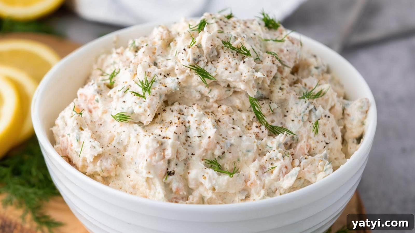 21 Snack Swaps That Beat Junk Food Without Sacrificing Flavor 8 A white bowl filled with salmon dip with cream cheese, garnished with dill and ground pepper.