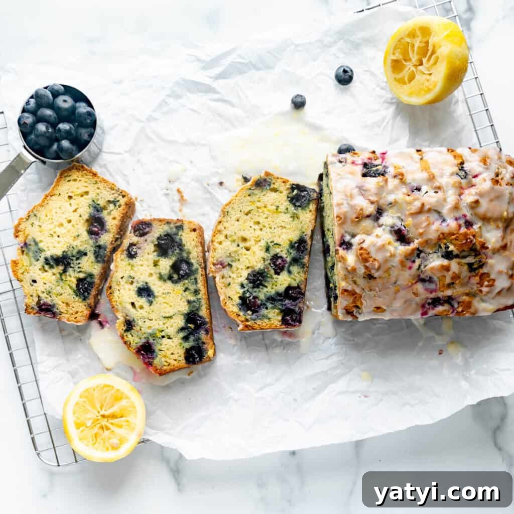 Copycat Starbucks Lemon Loaf Recipe: Moist Citrus Pound Cake Tutorial 11 Blueberry Zucchini Bread on white parchment paper with lemon and blueberries around it.