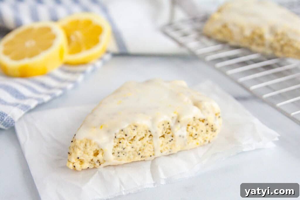 Copycat Starbucks Lemon Loaf Recipe: Moist Citrus Pound Cake Tutorial 14 A scone on white parchment paper dripping with glaze. Lemons and more scones in the background.